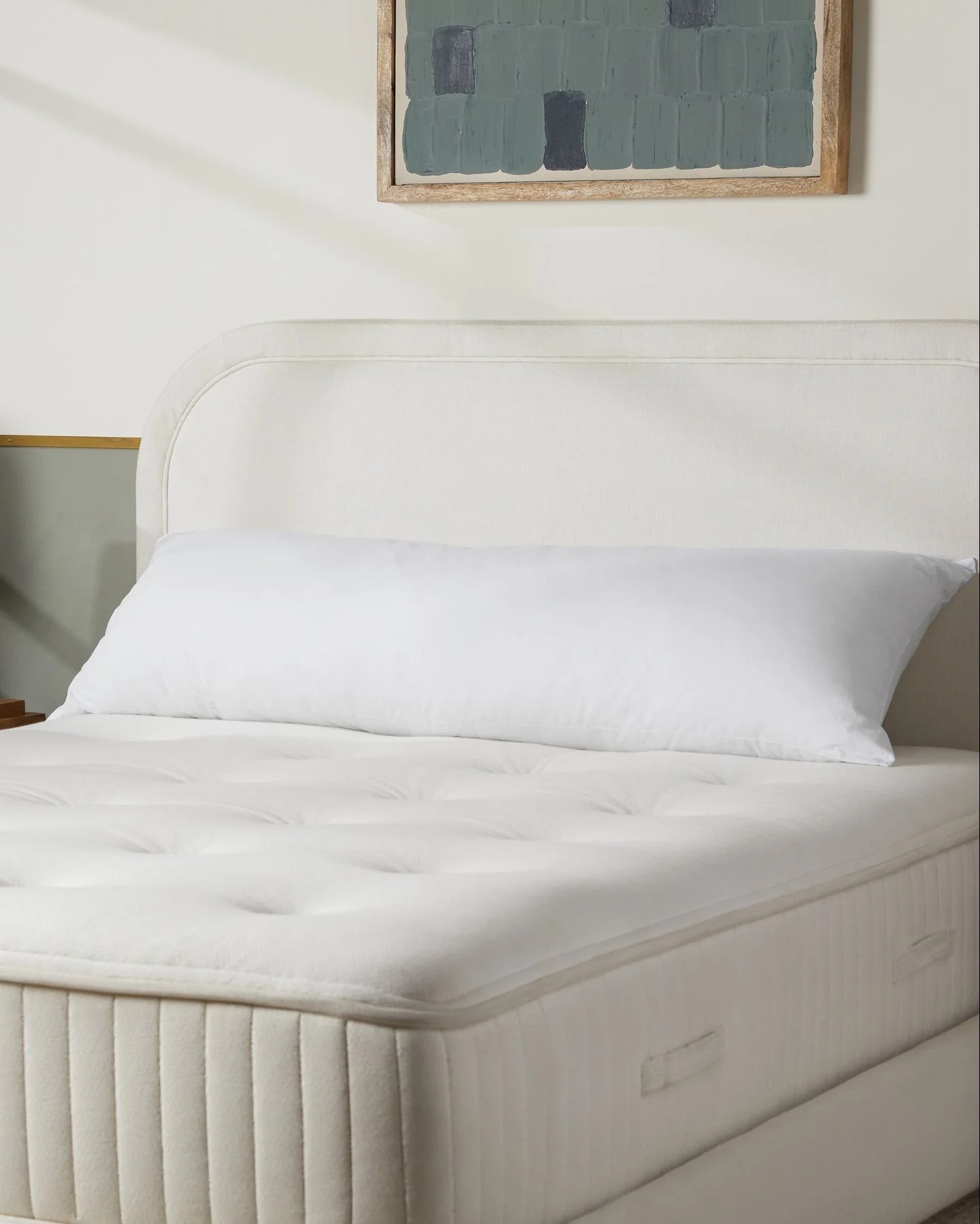 A white pillow on a bed.