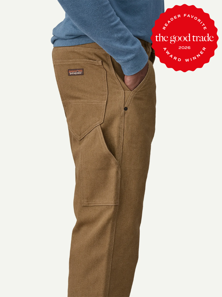 Person wearing brown work pants and a blue sweater, standing with a hand in the pocket. A red "The Good Trade 2026 Award Winner" badge is in the top right corner.