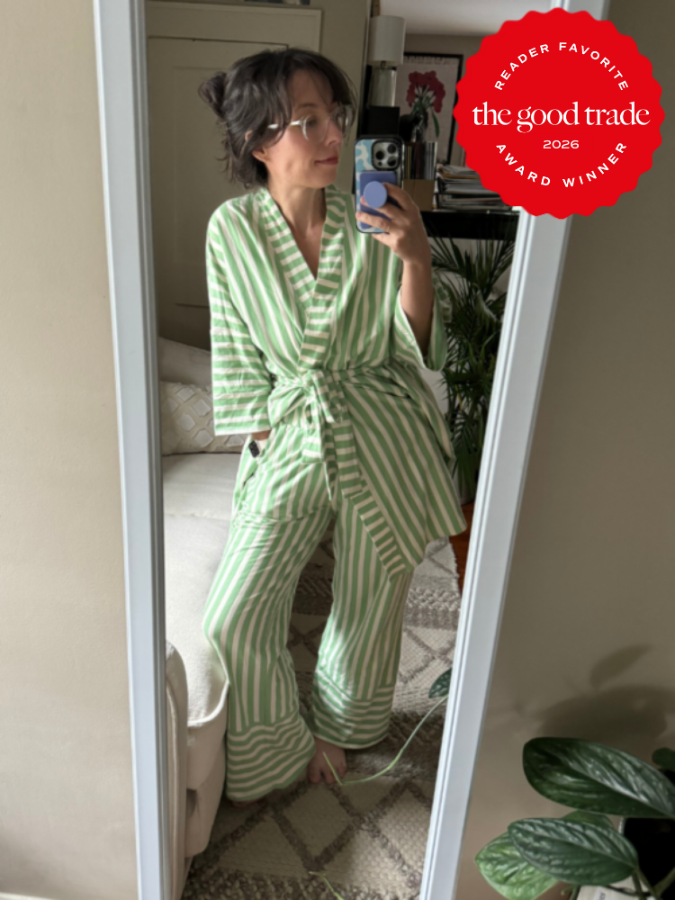 Person wearing green and white striped pajamas stands in front of a mirror, taking a selfie in a bedroom. A "The Good Trade 2026 Award Winner" badge appears in the image corner.