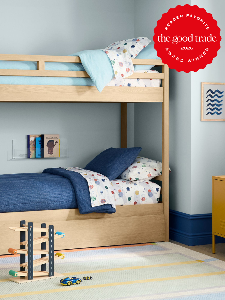 Children’s bedroom with wooden bunk beds, colorful bedding, wall art, toys on a striped rug, and a red “Reader Favorite: The Good Trade Award Winner 2026” badge in the top right corner.