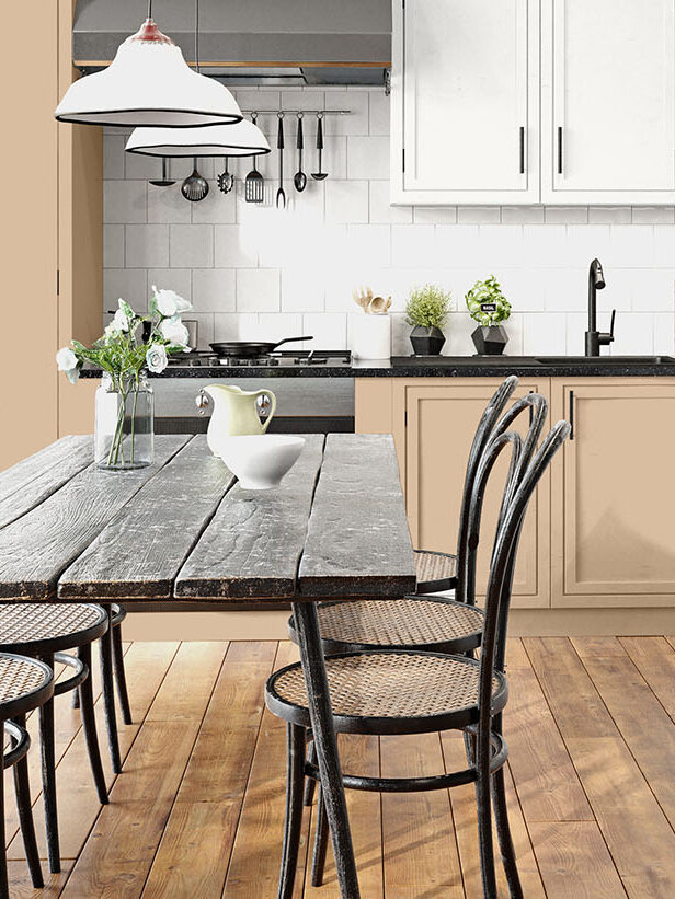 Modern kitchen with beige cabinets, black countertops, a rustic wooden dining table, six chairs, and potted plants on the counter and table.