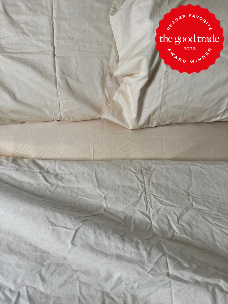 Unmade bed with rumpled cream-colored sheets and pillows; a red badge in the top right corner reads "The Good Trade 2026 Award Winner Reader Favorite.