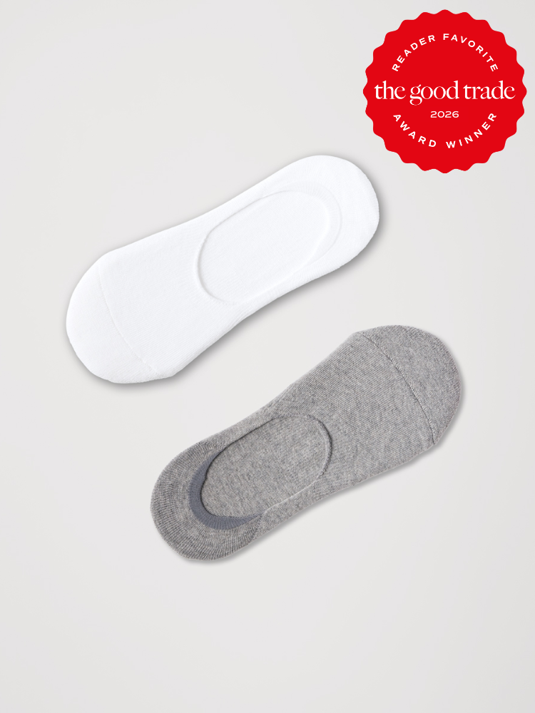 A pair of organic no-show socks, one white and one gray, on a light background with a red “The Good Trade Award Winner 2026” badge in the top right corner.