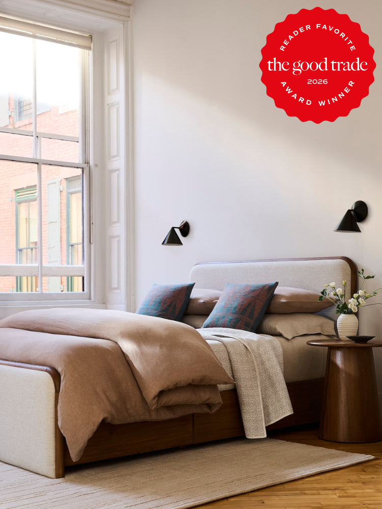 A bed with pillows and a vase of flowers on a table.