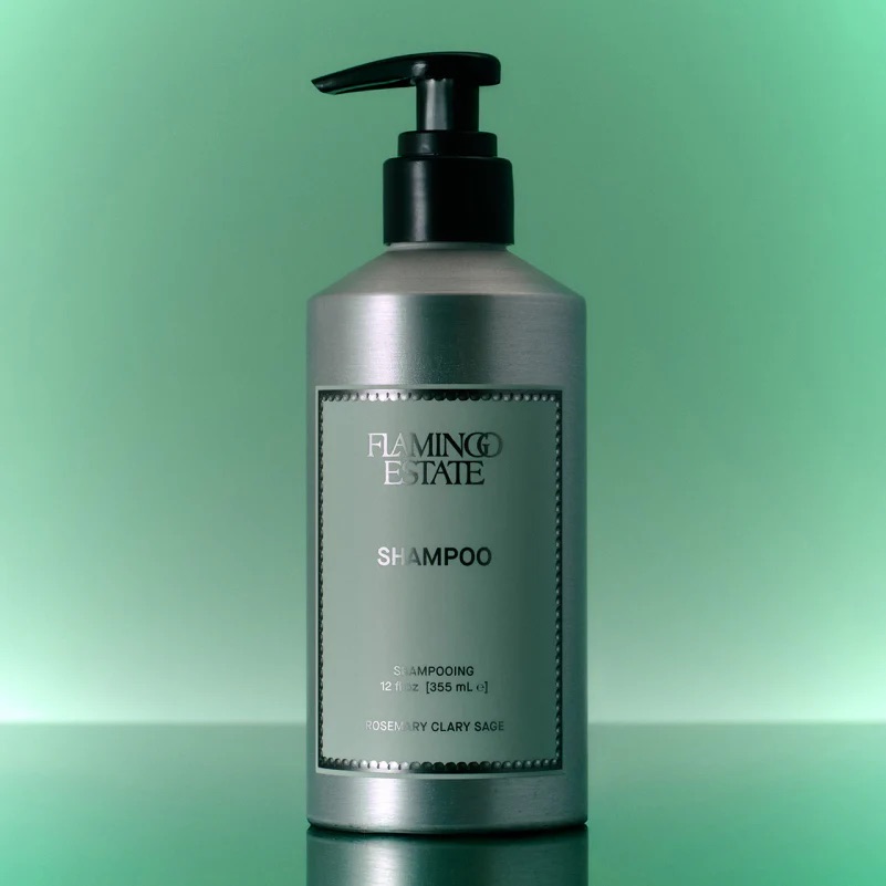 A silver pump bottle labeled “Flamingo Estate Shampoo” stands against a green gradient background.