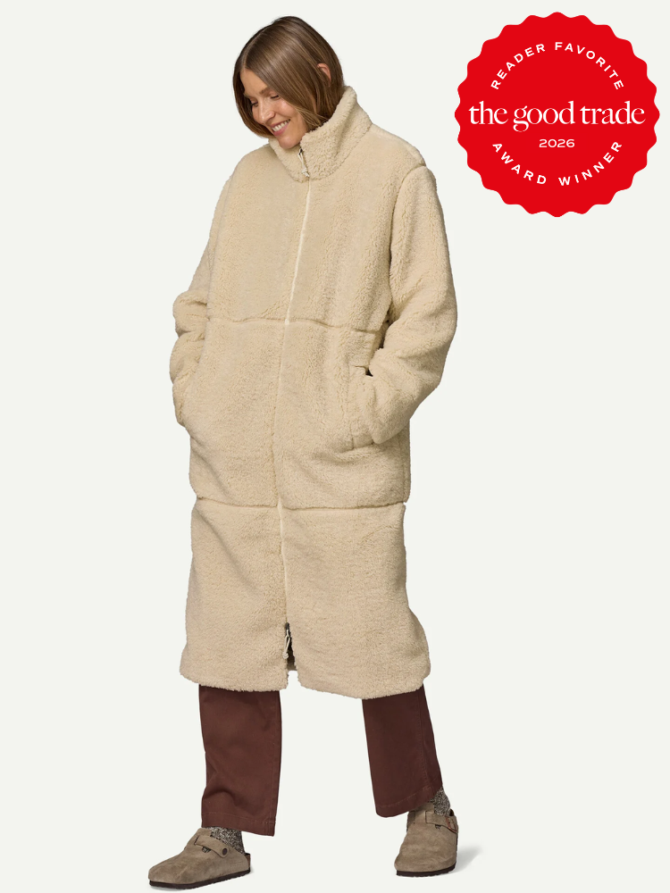 Person wearing a long, beige, fleece coat with hands in pockets, brown pants, and beige shoes. "The Good Trade 2026 Reader Favorite Award Winner" badge in the top right corner.