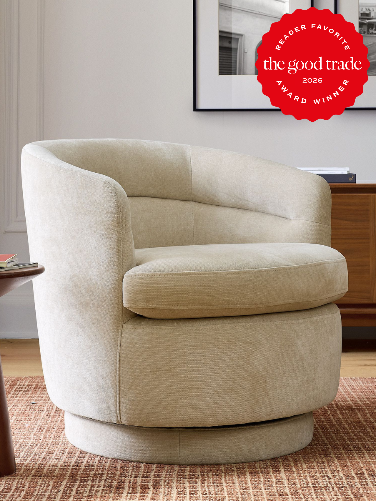 A beige swivel chair on a brown textured rug, next to a wooden cabinet. A "The Good Trade Award Winner 2026" badge is in the top right corner.