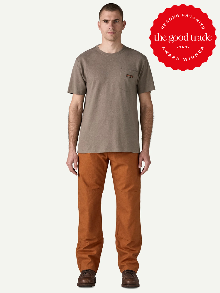 A man stands facing forward, wearing a taupe t-shirt, rust-colored pants, and brown shoes. A red badge in the corner reads "The Good Trade Award Winner 2026 Reader Favorite.