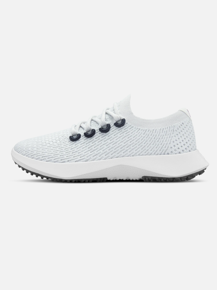 A white athletic sneaker with a textured mesh upper, black eyelets, white laces, and a thick white sole with a gray tread, shown in a side profile view.