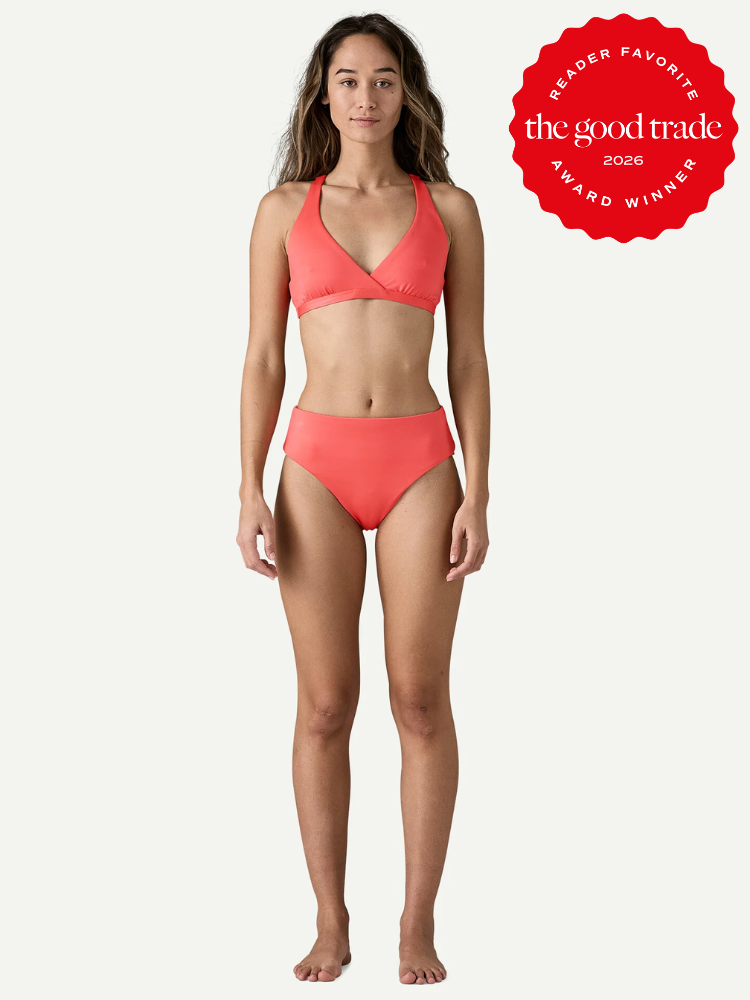 A woman stands facing forward, wearing a coral bikini. A red badge on the right reads “The Good Trade Award Winner 2026 Reader Favorite.”.