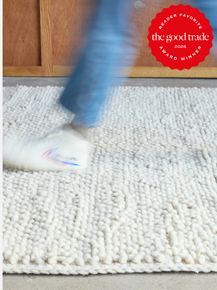 A person in blue jeans and white shoes walks on a textured, off-white rug; a red "The Good Trade 2026 Award Winner" badge appears in the top right corner.