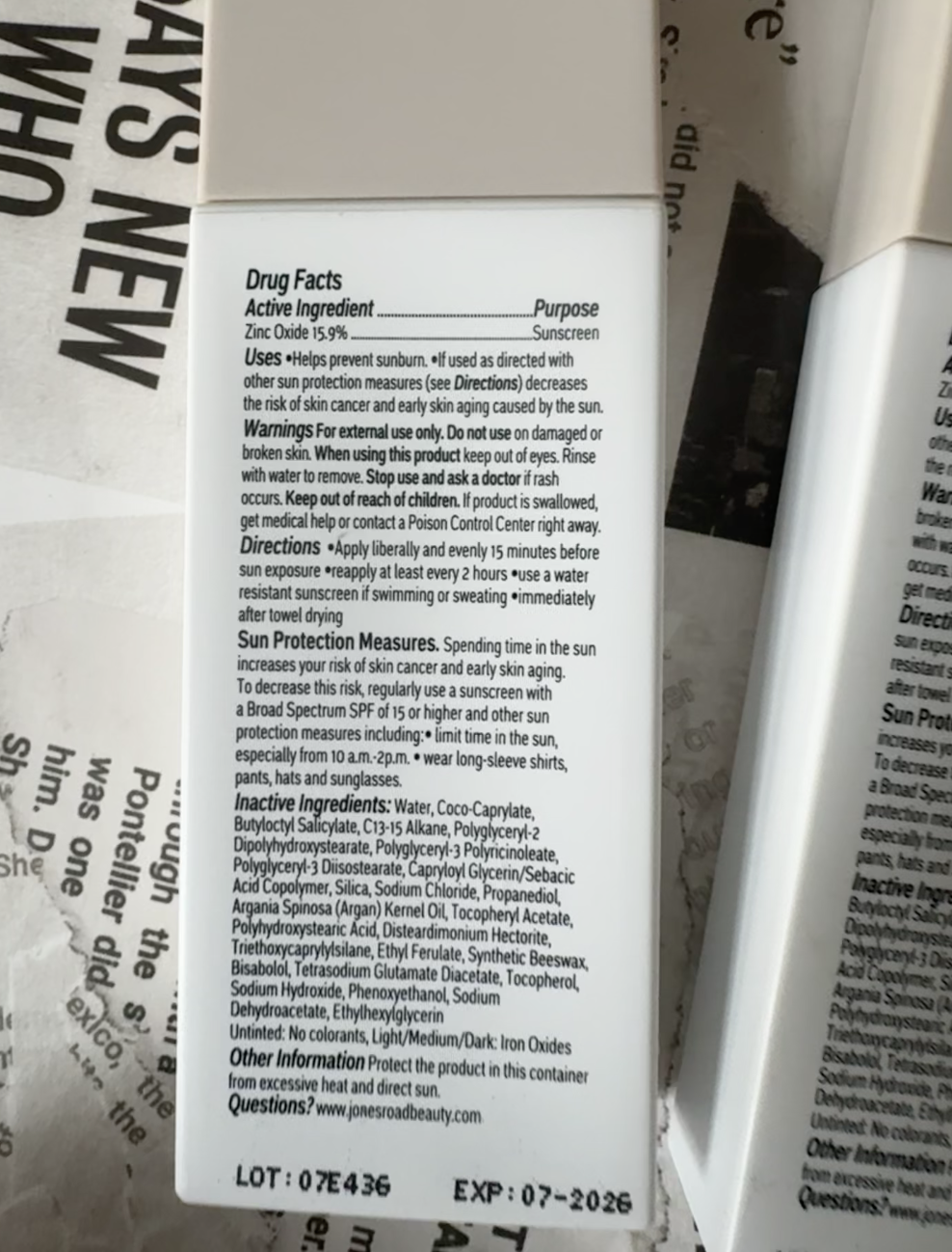 Close-up of an Ilia sunscreen bottle label showing drug facts, active ingredient (zinc oxide 15%), uses, warnings, directions, ingredients, and expiration date of 07-2026.