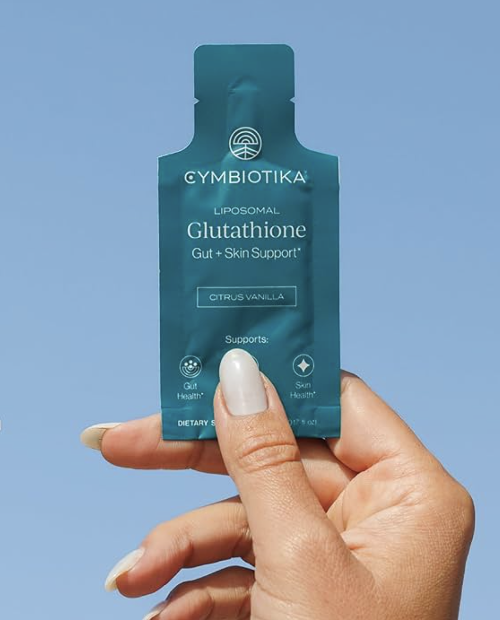 A hand holding a Cymbiotika Liposomal Glutathione dietary supplement packet against a clear blue sky.
