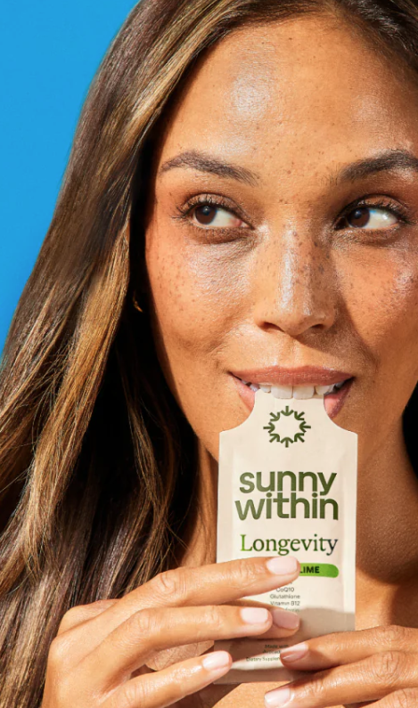 A woman with long brown hair holds a "Sunny Within Longevity Lime" sachet close to her mouth, about to open it, with a bright blue background.