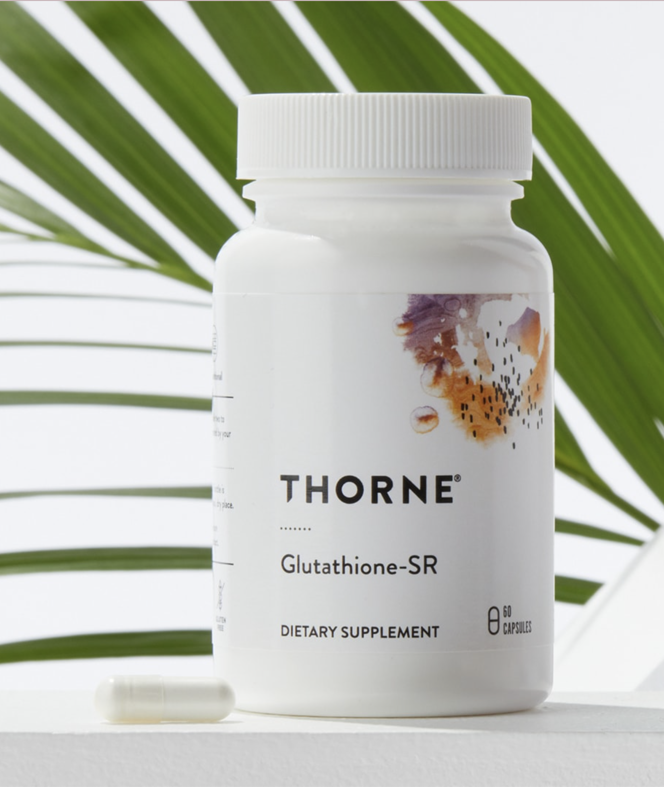 A bottle of Thorne Glutathione-SR dietary supplement with 60 capsules, shown next to a single capsule and a green leaf in the background.