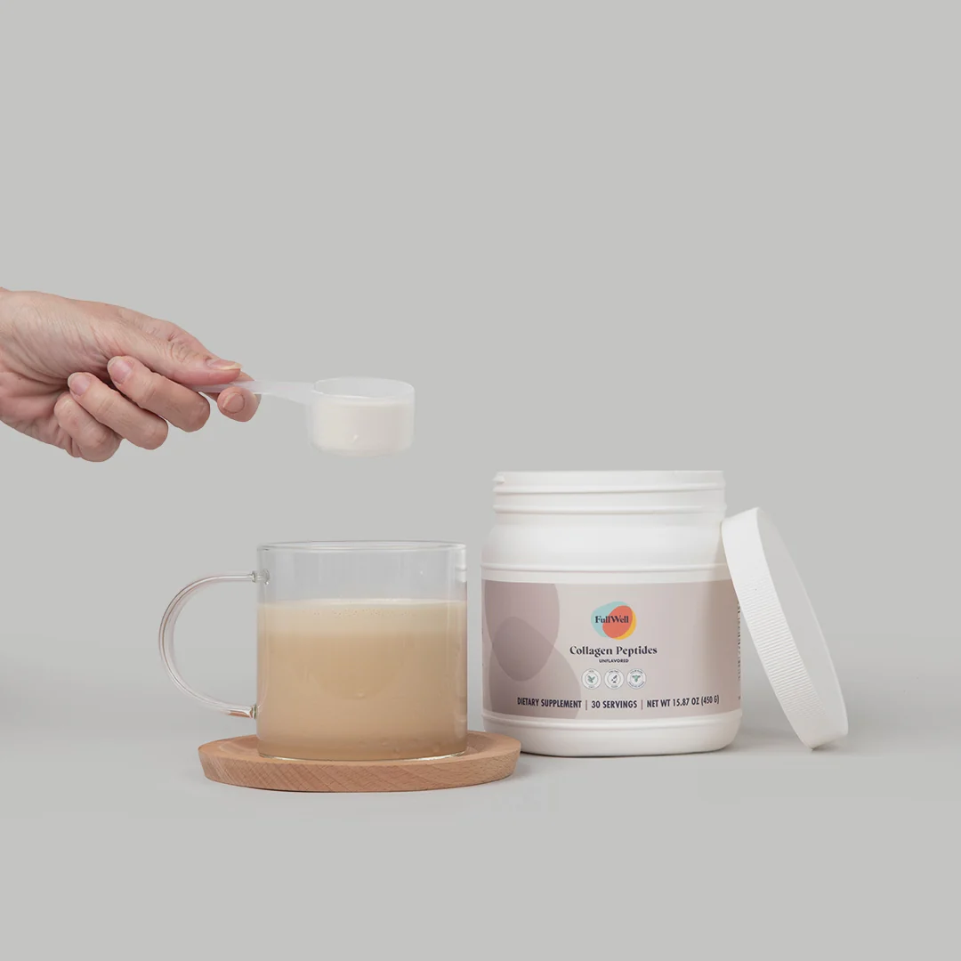 A hand adds a scoop of powder to a glass mug of coffee next to an open container labeled "Collagen Peptides" on a neutral background.