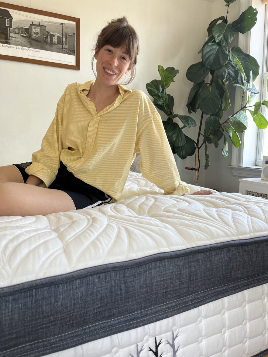 A woman sits comfortably on an organic mattress, enjoying a peaceful moment of relaxation.