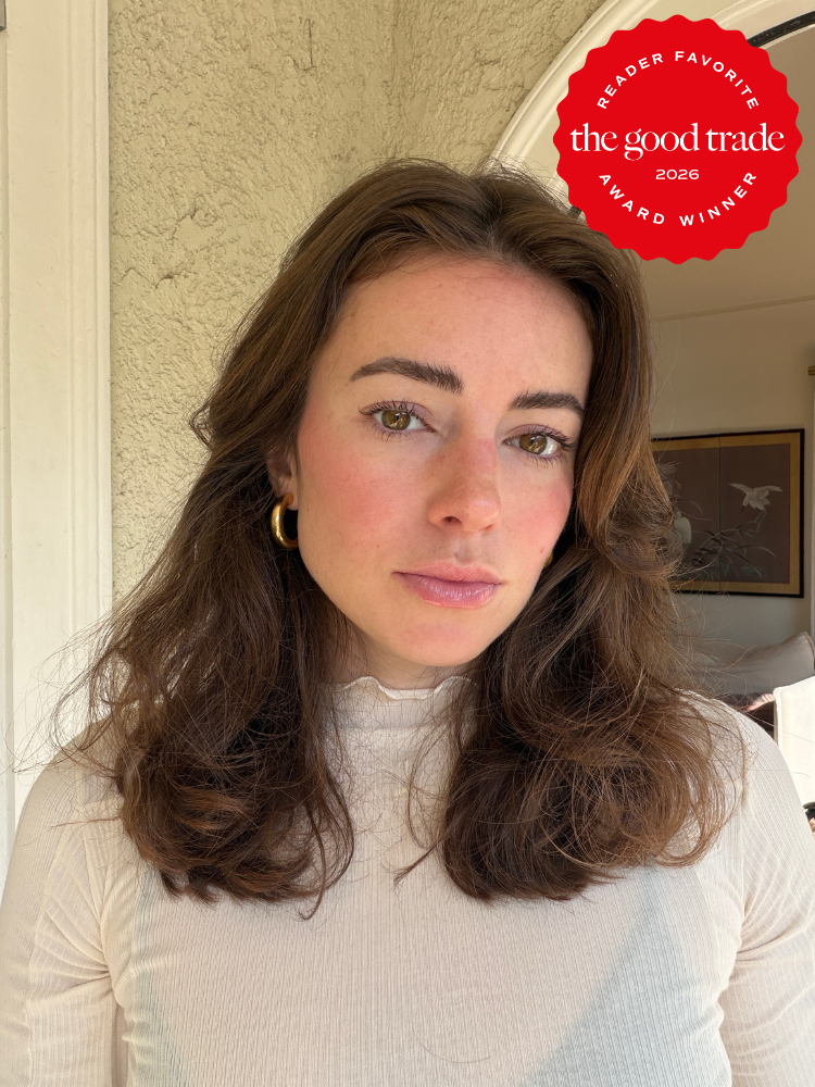 A woman with wavy brown hair and a neutral expression stands indoors wearing a light turtleneck. A red "The Good Trade Reader Favorite 2026 Award Winner" badge is in the top right corner.