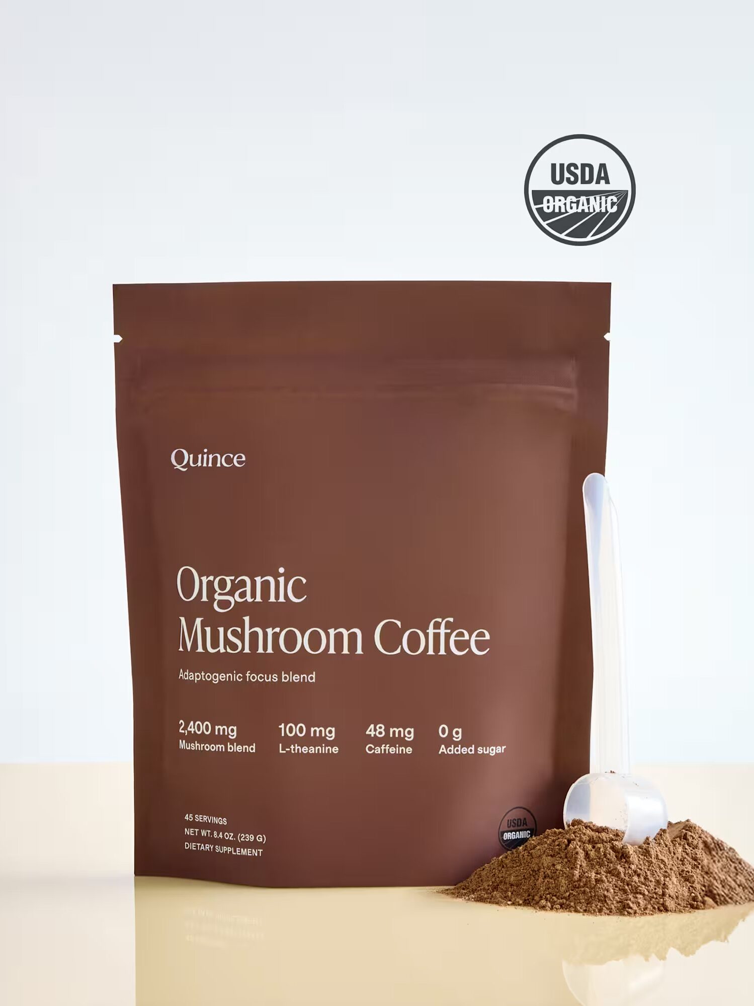 A brown bag labeled "Organic Mushroom Coffee" by Quince is shown with a clear scoop and loose coffee powder beside it; a USDA Organic seal appears above the bag.