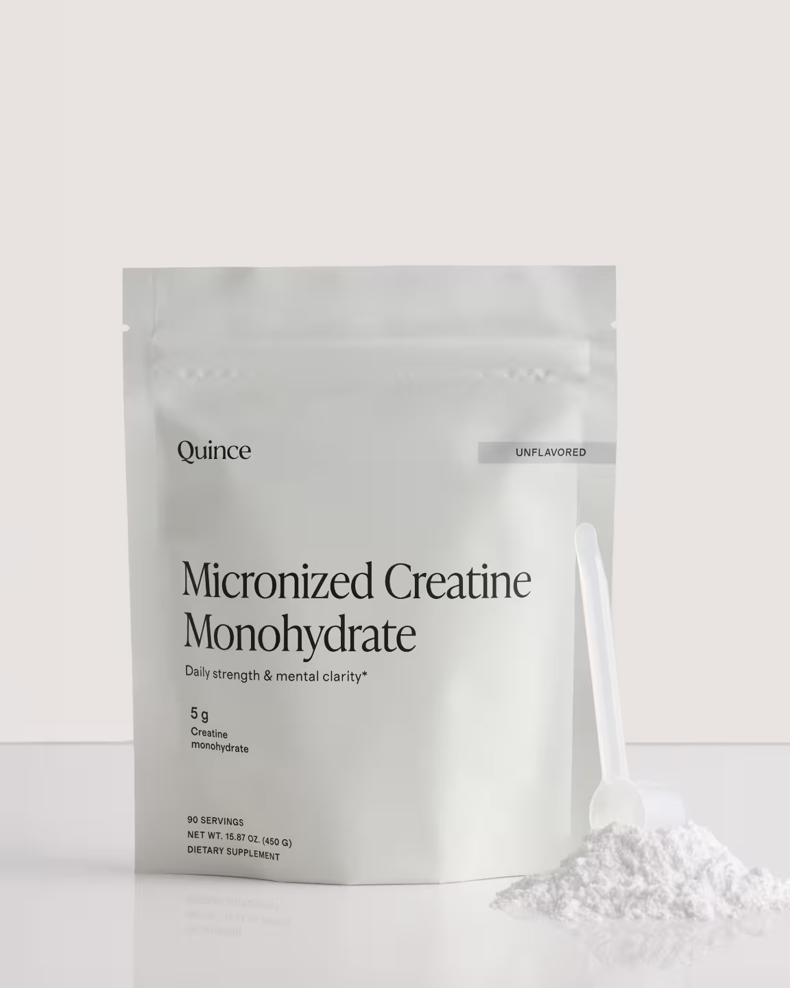 A white pouch labeled “Micronized Creatine Monohydrate” stands upright with a scoop and powder beside it.