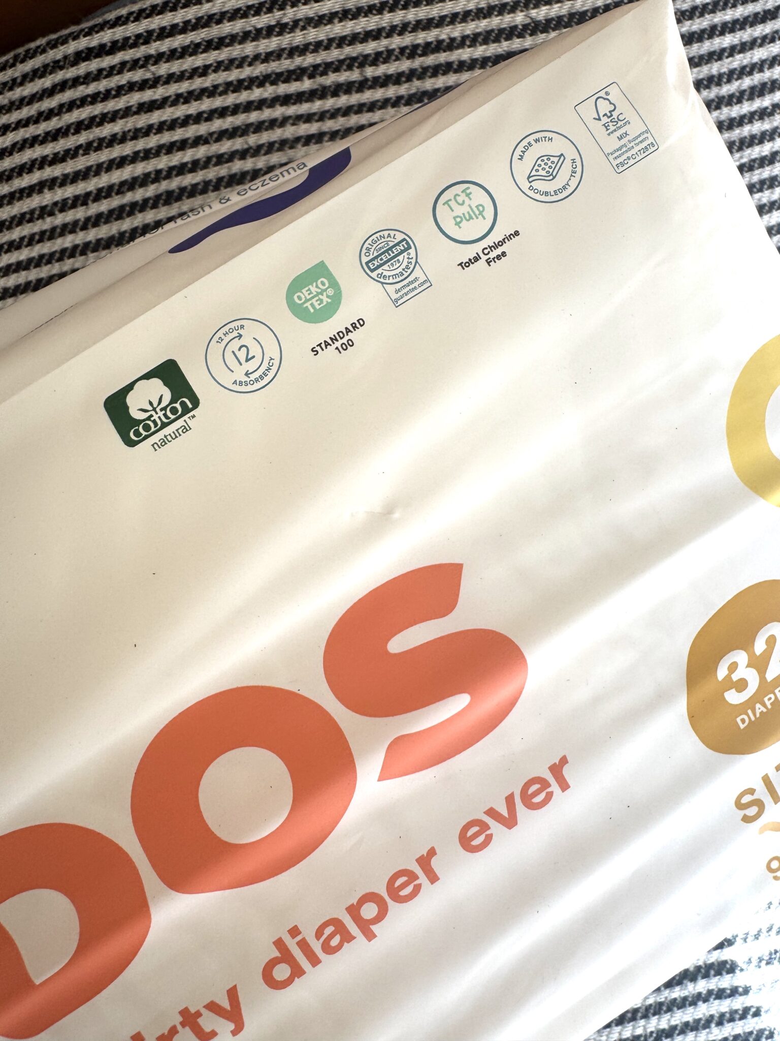 A package of diapers on a striped surface, featuring eco-friendly certifications and the text "diaper ever" in large letters.