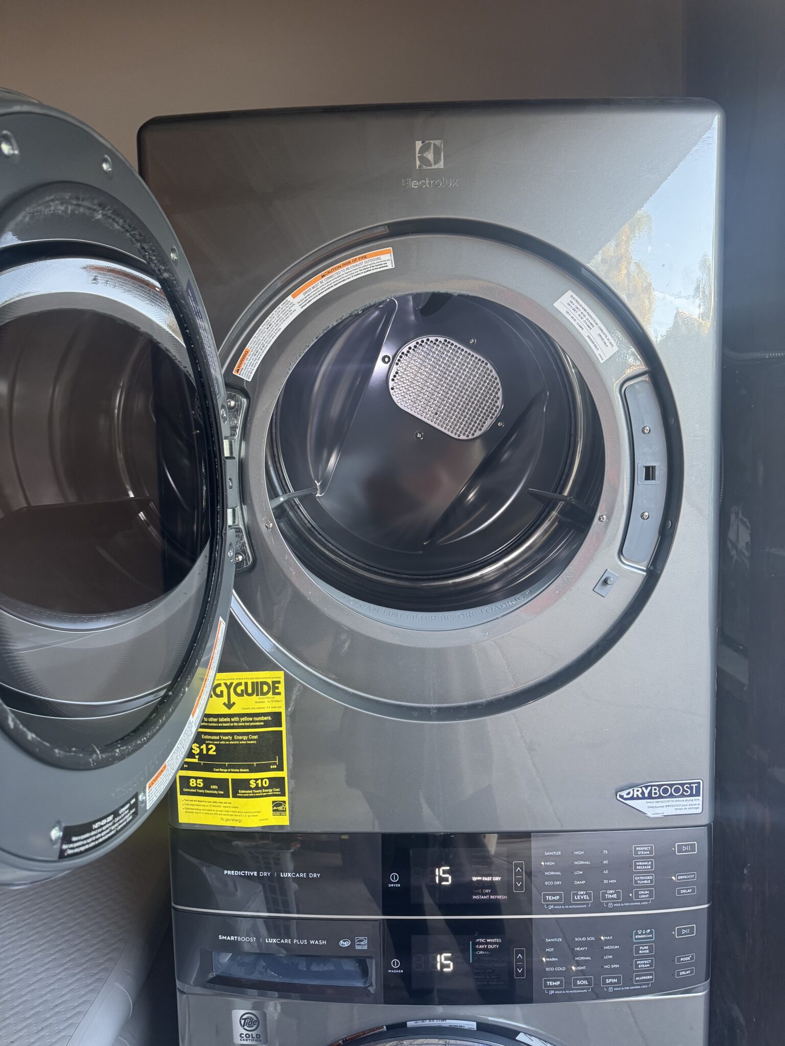 Front-loading Electrolux dryer with the door open, displaying an empty drum and control panel; energy guide label is visible on the front.