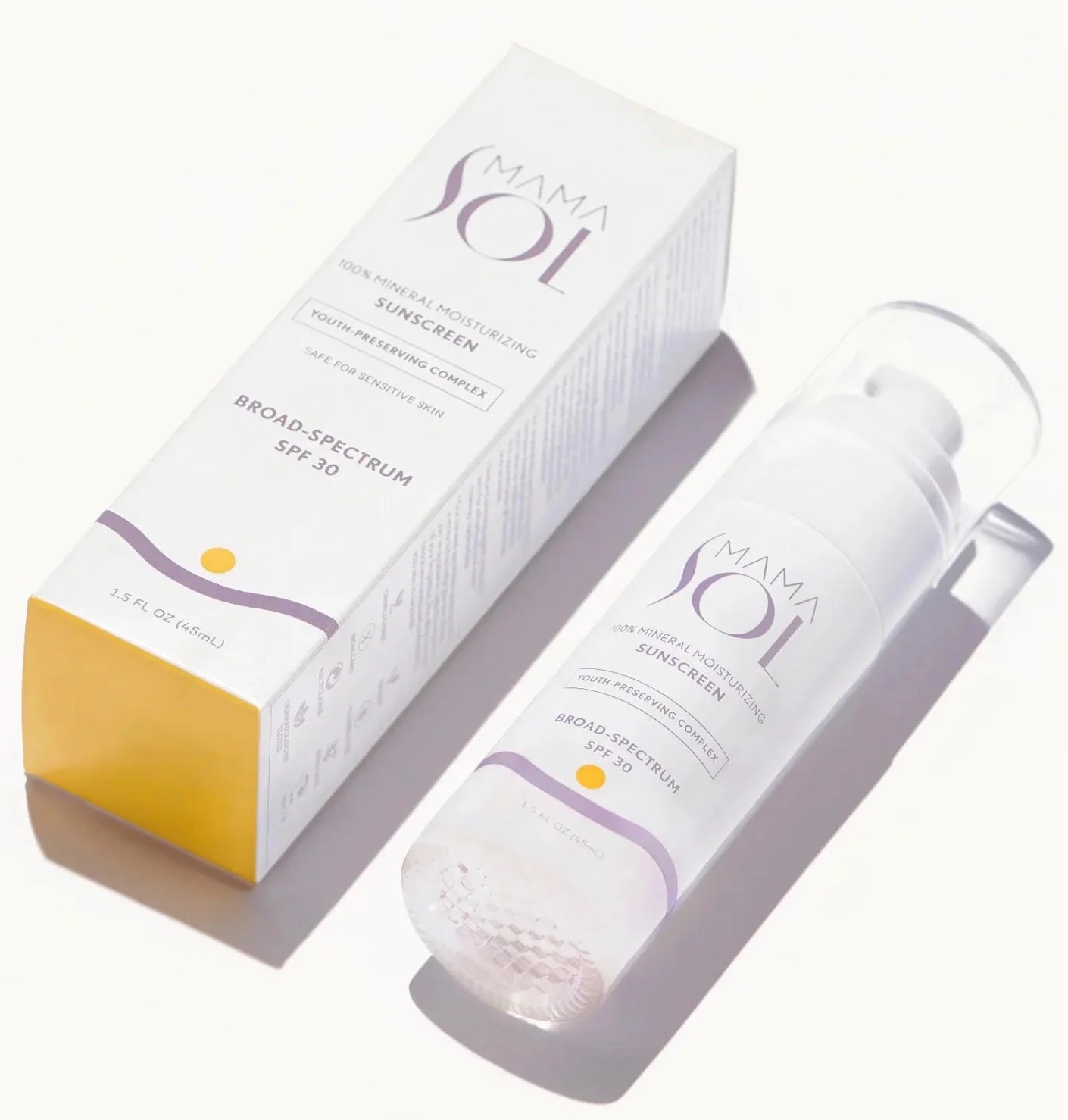 A bottle of Mama Sol Broad-Spectrum SPF 30 sunscreen stands beside its matching box, both white with purple and yellow accents, shown on a white background.