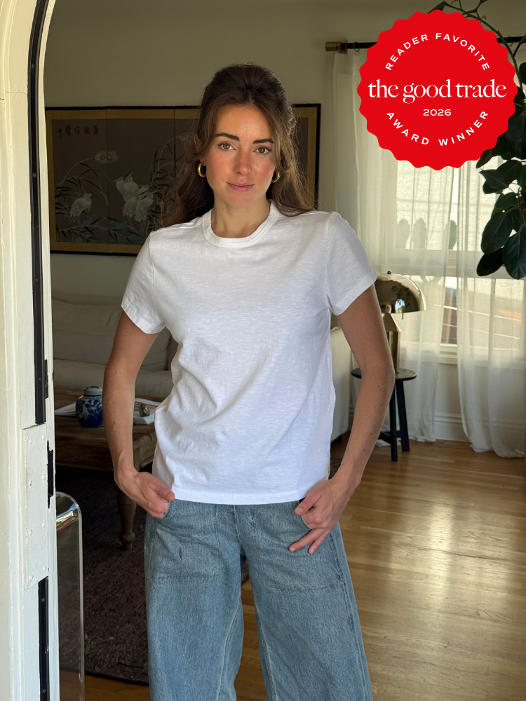 A woman in a white t-shirt and jeans stands indoors. A red "The Good Trade Reader Favorite Award Winner 2026" badge is in the upper right corner of the image.