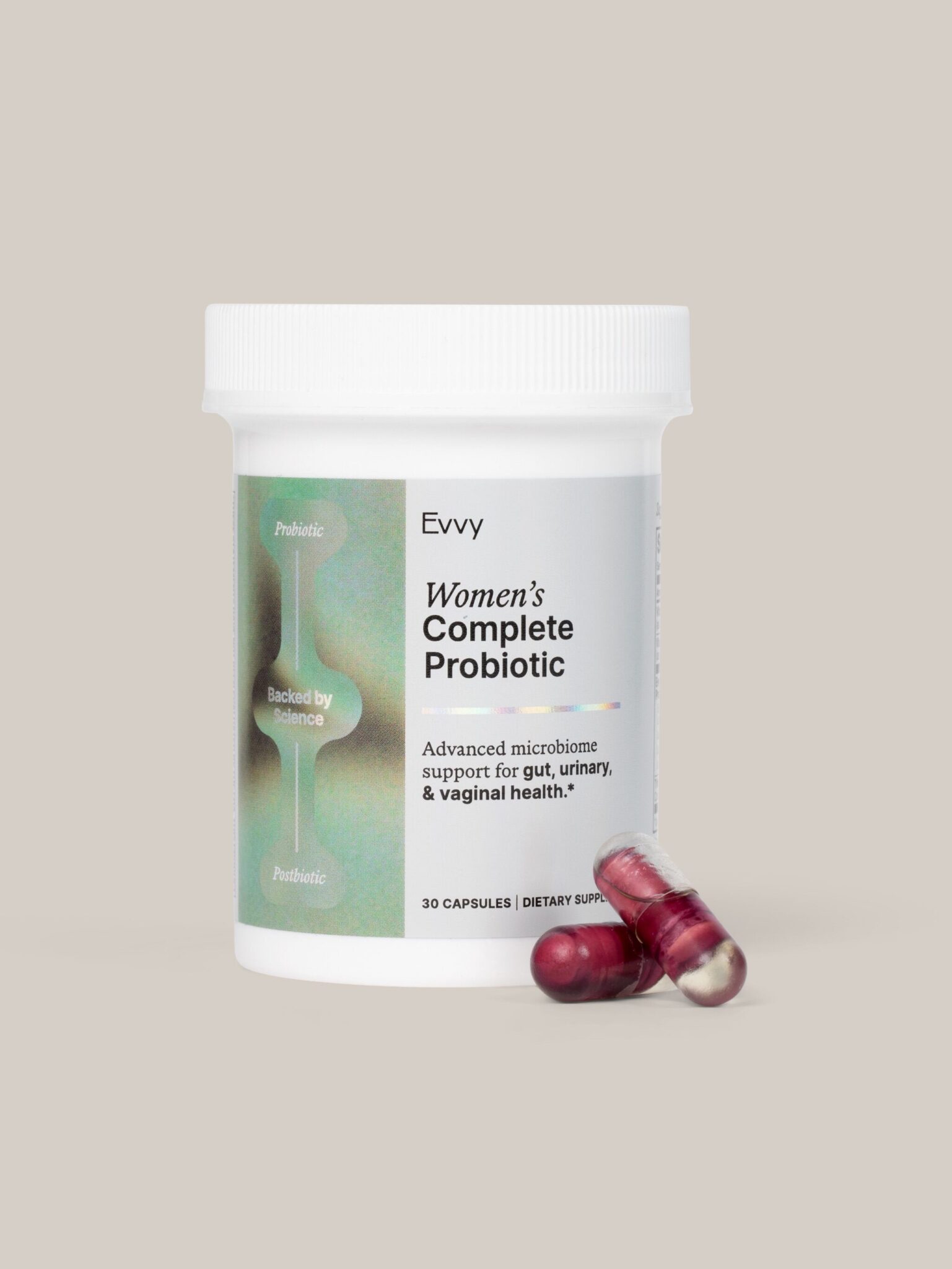 A white bottle labeled "Evvy Women's Complete Probiotic" with two red capsules placed beside it, set against a plain beige background.