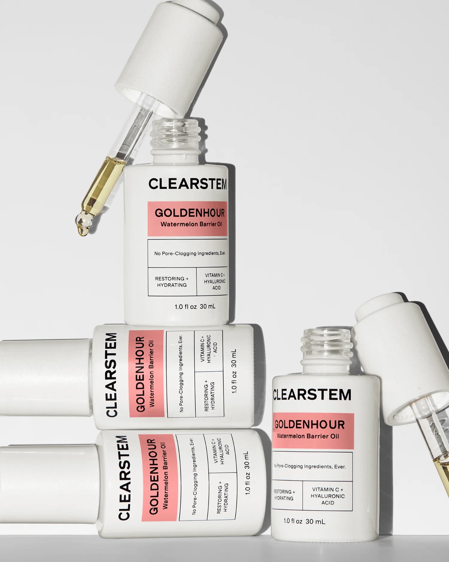 Four bottles of CLEARSTEM Goldenhour Watermelon Barrier Oil are shown, with droppers and product labels visible, arranged in a stacked composition on a white background.
