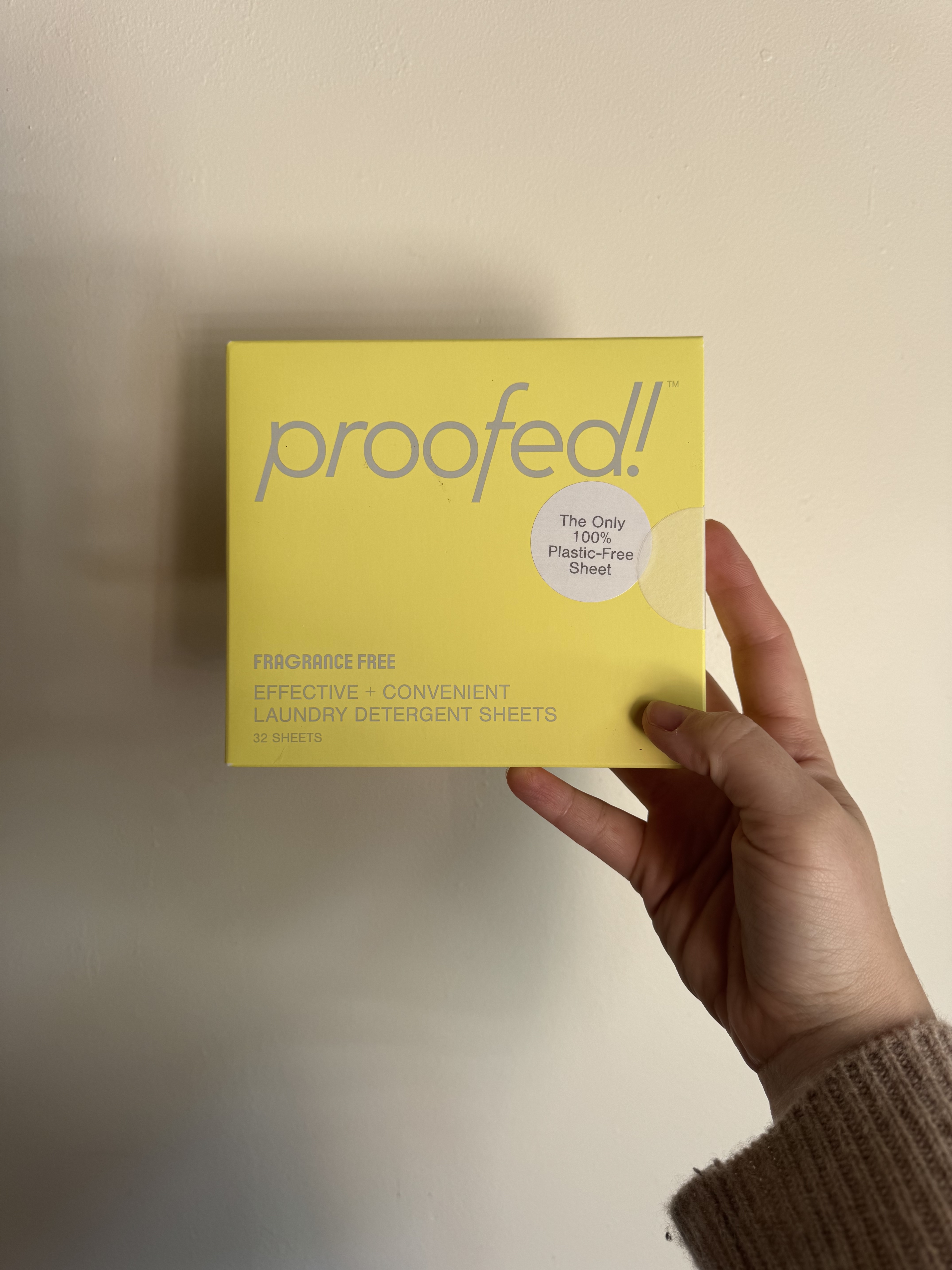 A hand holds a yellow box labeled "proofed!" containing fragrance-free, convenient laundry detergent sheets with 32 sheets per box.