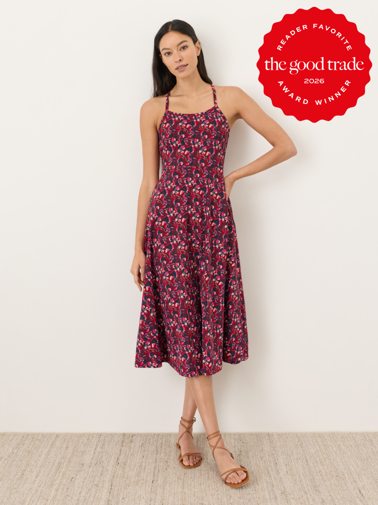 Woman wearing a sleeveless, floral-patterned midi dress stands against a white wall. A red badge reads "The Good Trade Reader Favorite Award Winner 2026.