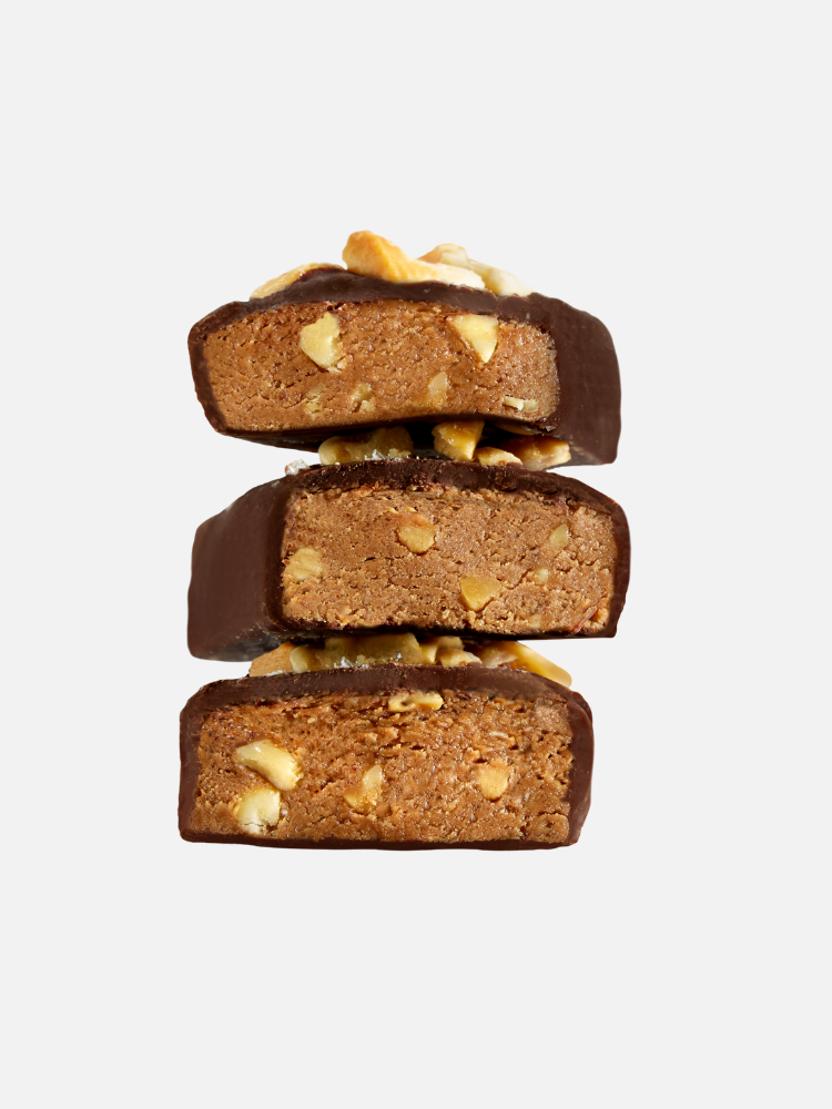 Three chocolate-coated protein bars with visible nuts are stacked on top of each other against a plain white background.