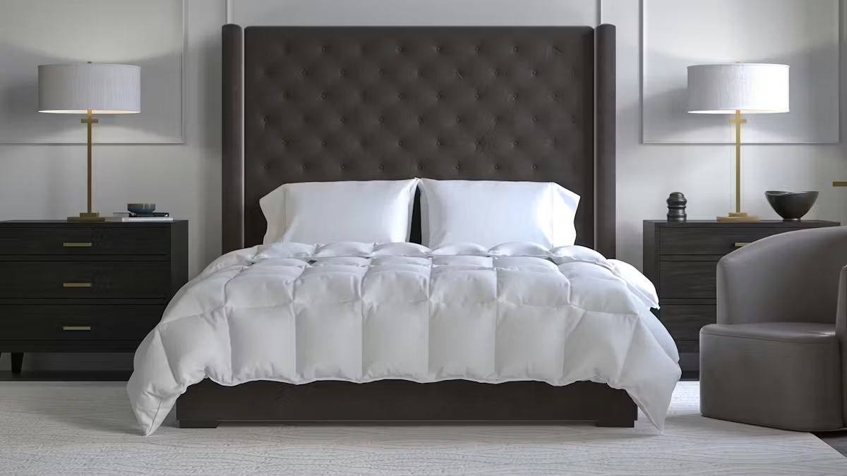 A modern bedroom with a dark tufted headboard, white bedding, two white pillows, two matching bedside tables with lamps, and a gray armchair.