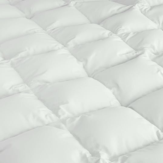 Close-up of a white, quilted fabric surface, resembling a padded mattress or comforter with square stitched sections.