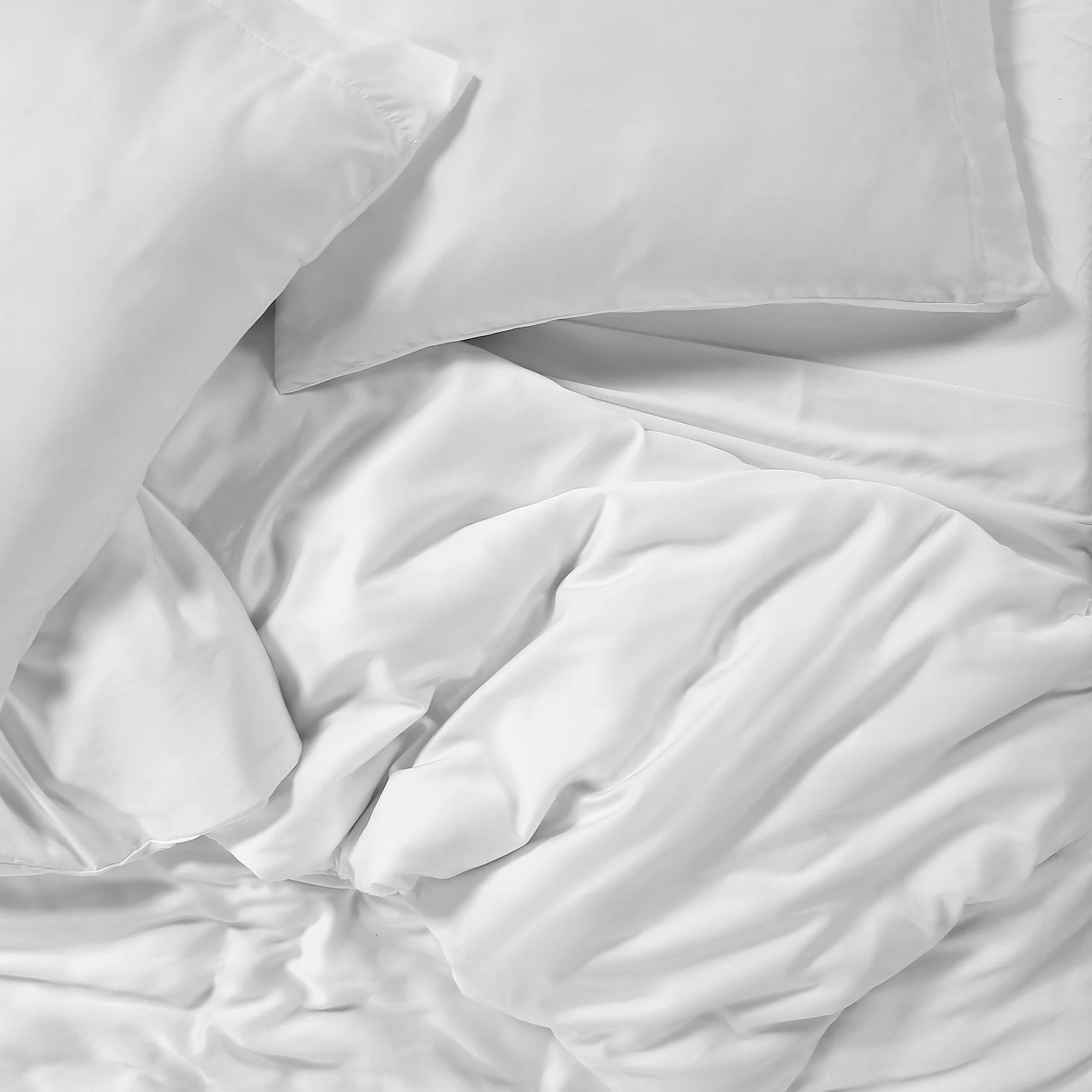 White satin bed sheets and pillowcases are shown in a slightly rumpled state.