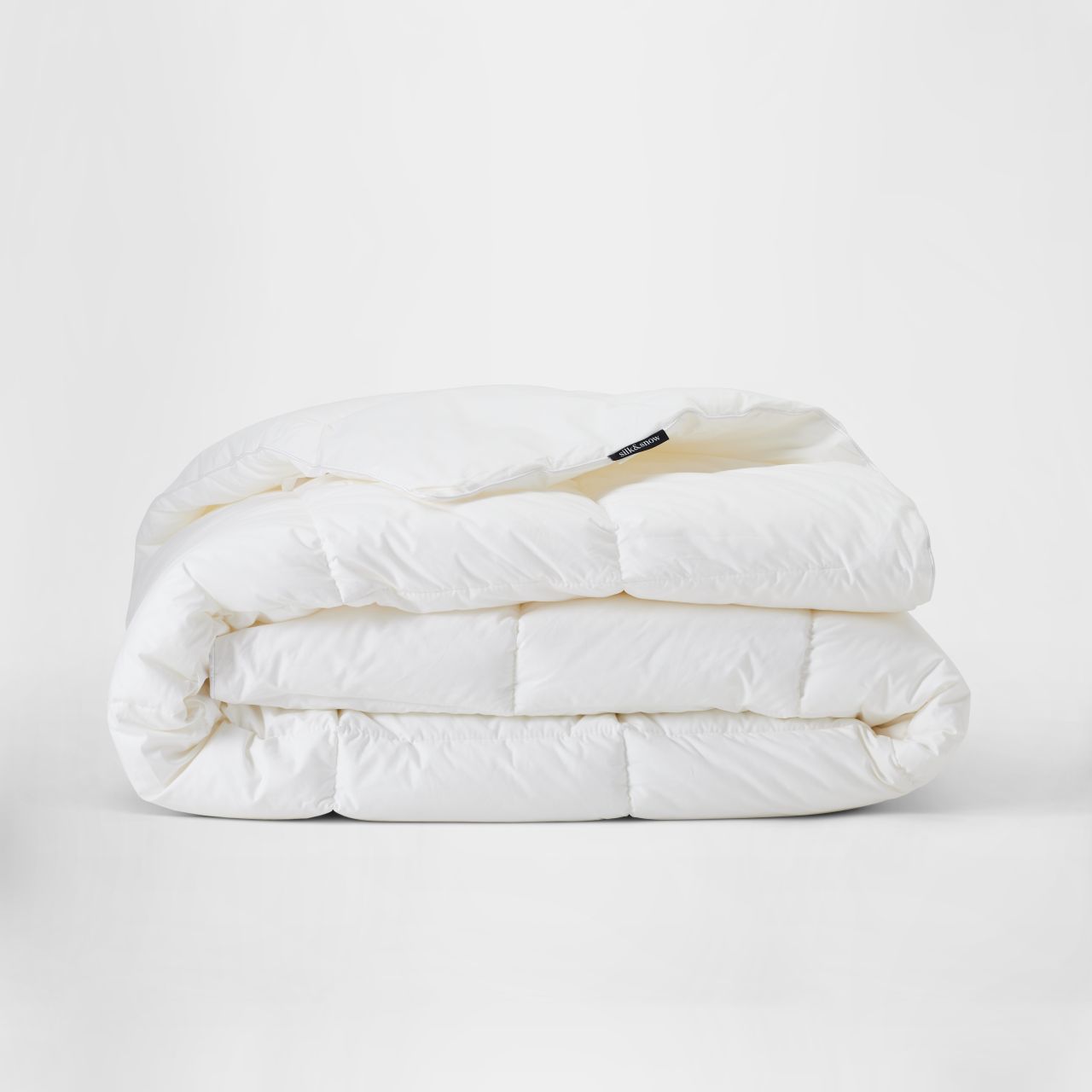 A neatly folded white comforter is placed against a plain white background.