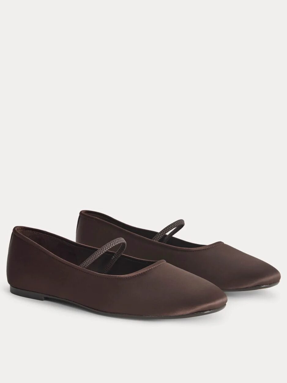 A pair of brown ballet flats with a single thin strap across the top, shown on a plain light background.