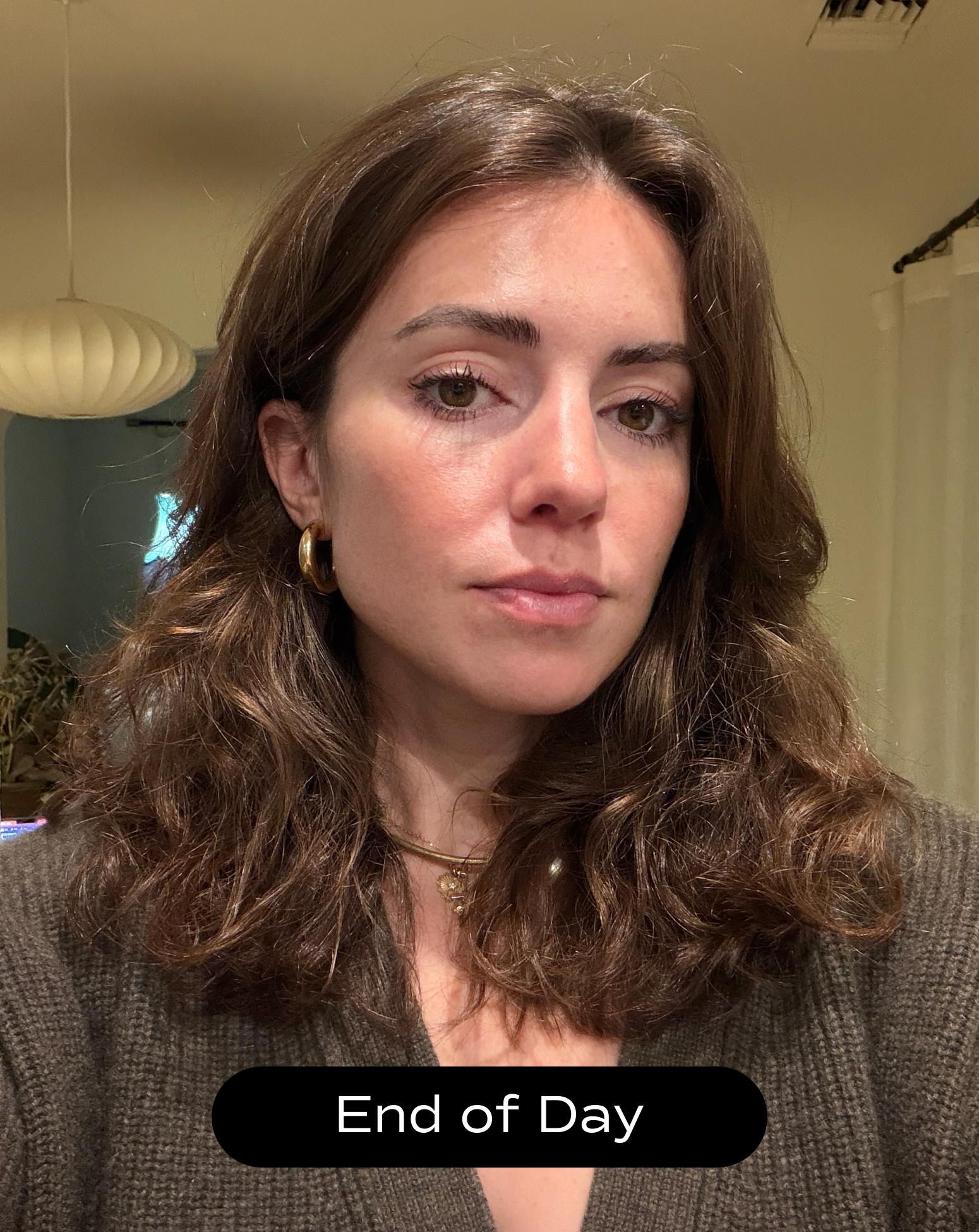 A woman with wavy brown hair and gold hoop earrings looks at the camera in indoor lighting. Text at the bottom reads "End of Day.