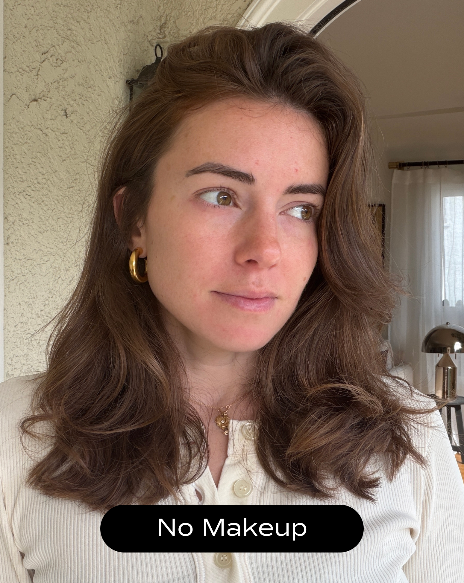 A woman with long brown hair and no visible makeup looks slightly to the side in a softly lit indoor setting. A label at the bottom reads "No Makeup.