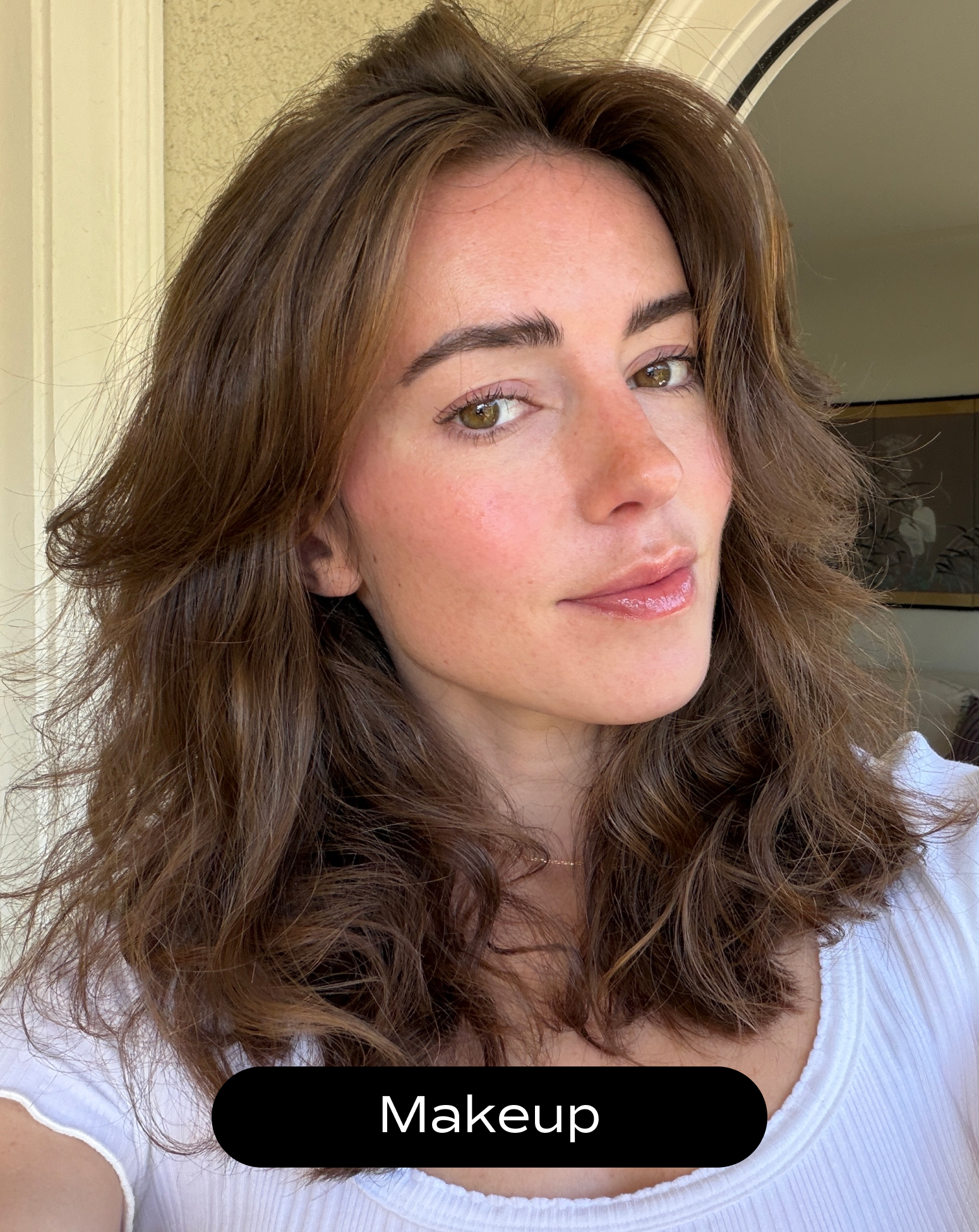 A woman with wavy brown hair wearing light makeup and a white top looks at the camera. The word "Makeup" is displayed at the bottom of the image.