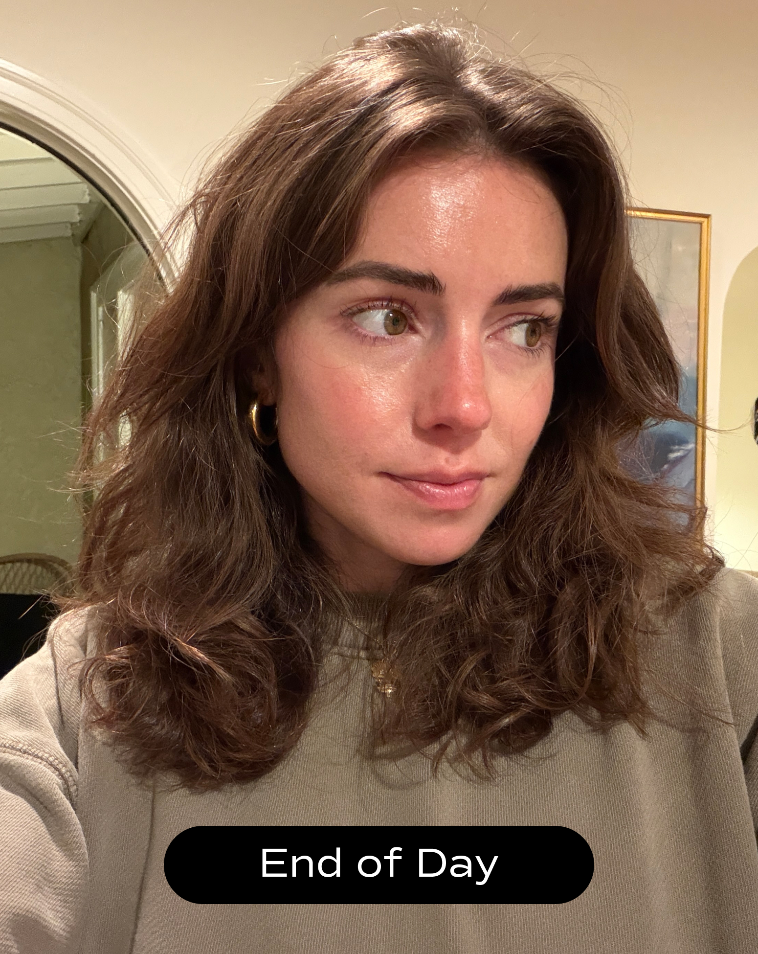 A woman with wavy brown hair and a neutral expression looks to the side, wearing a grey sweatshirt indoors. The text "End of Day" is displayed at the bottom.