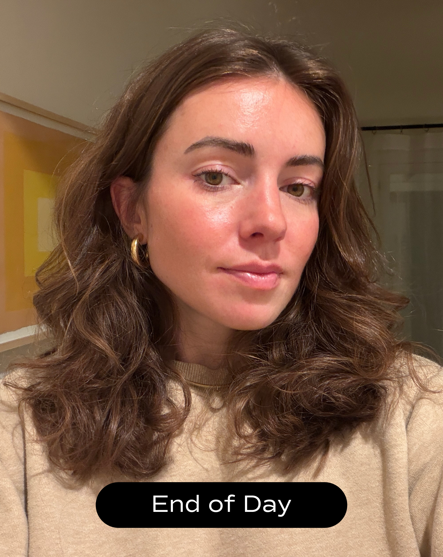 A woman with wavy brown hair and gold hoop earrings looks at the camera indoors; the text "End of Day" appears at the bottom of the image.