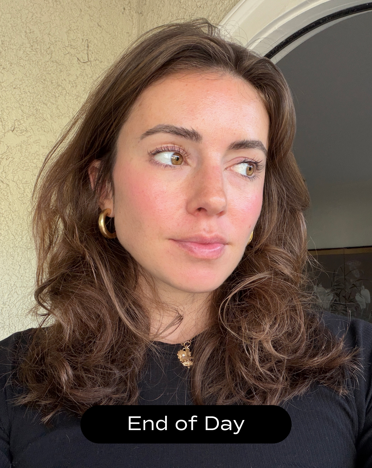 A woman with wavy brown hair and gold earrings looks to the side, standing indoors near a door. Text at the bottom reads "End of Day.