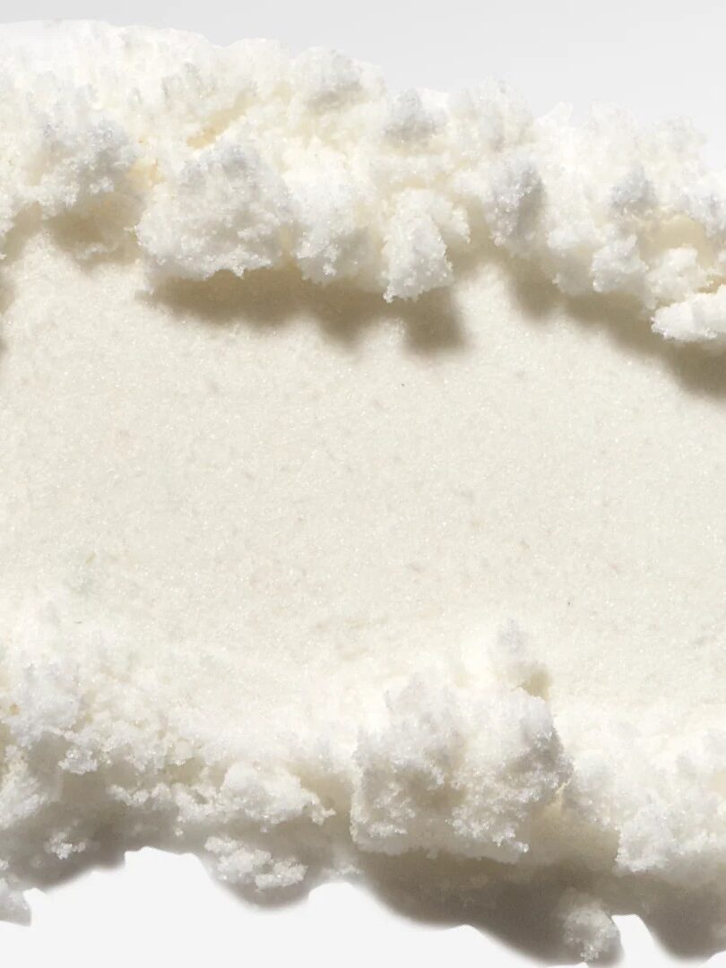 Close-up of a white, powdery substance with a rough, textured edge on a light background.