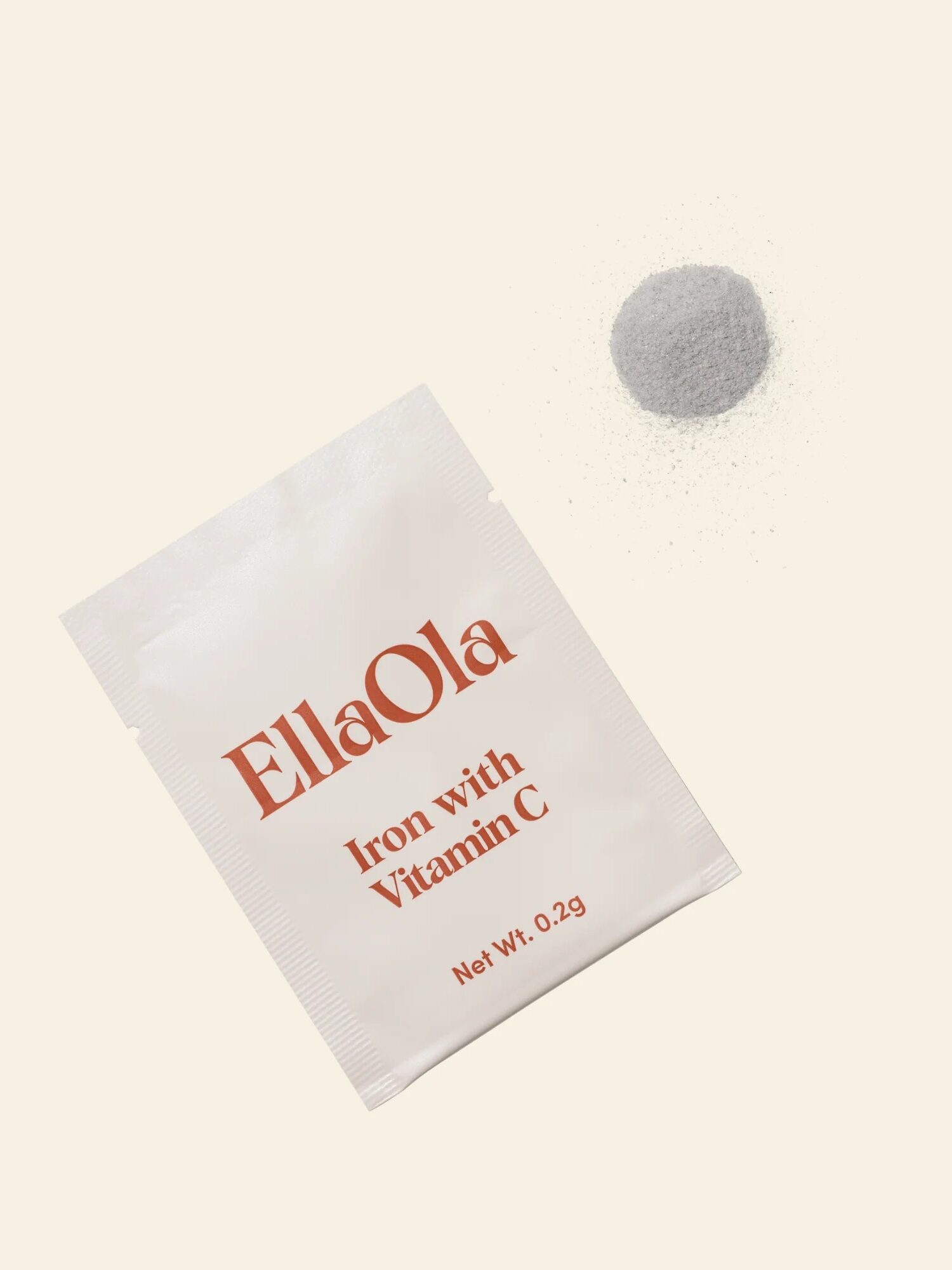 A packet labeled "EllaOla Iron with Vitamin C" lies next to a small pile of grey powder on a light beige background.