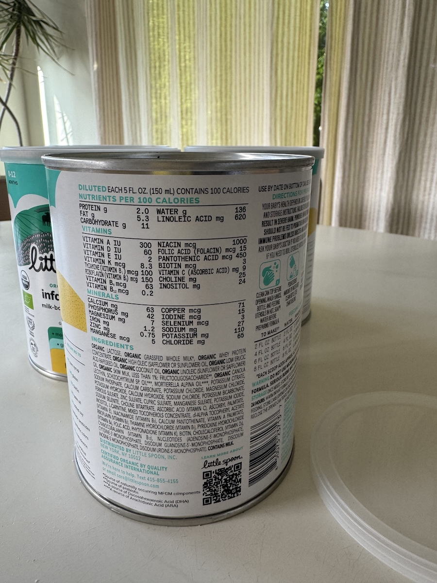 A can of infant formula on a table, showing the nutrition facts, ingredients, and preparation instructions printed on the label.