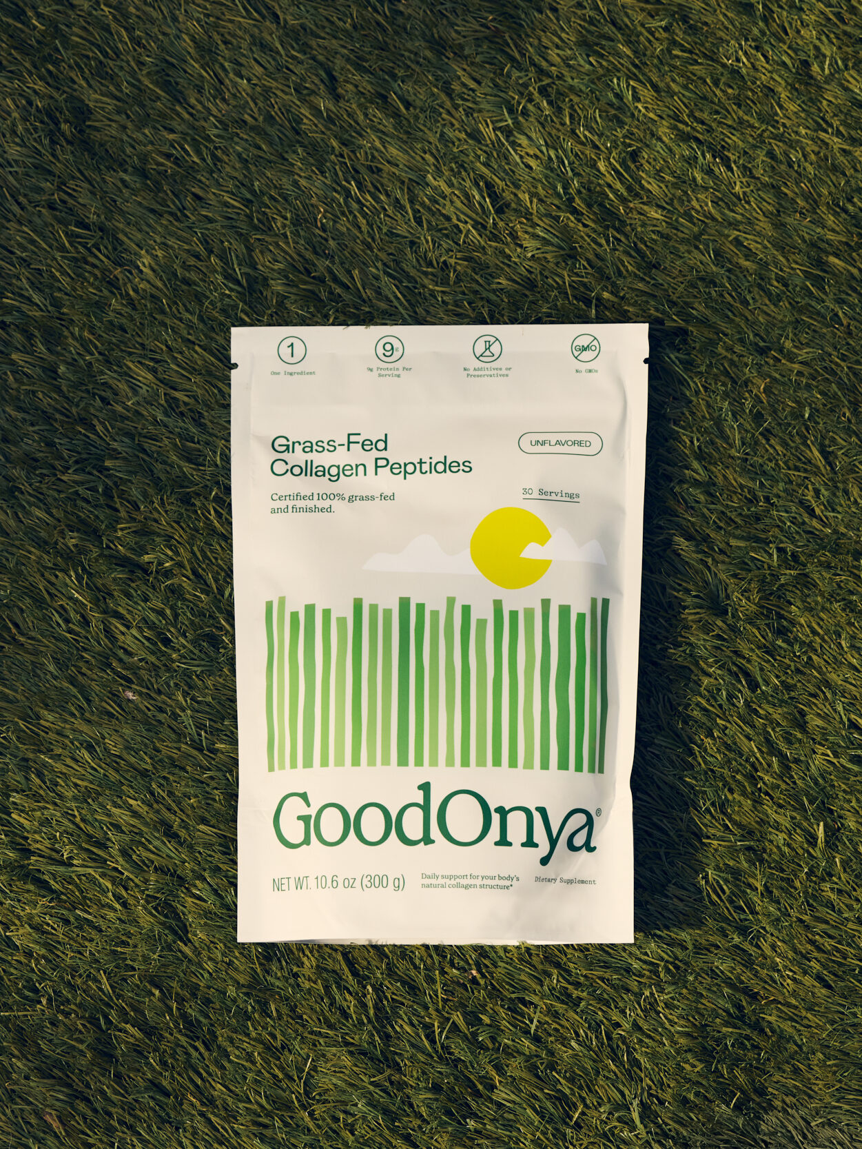 A bag of GoodOnya Grass-Fed Collagen Peptides lies on green grass, showing product branding and nutritional information on the front of the package.