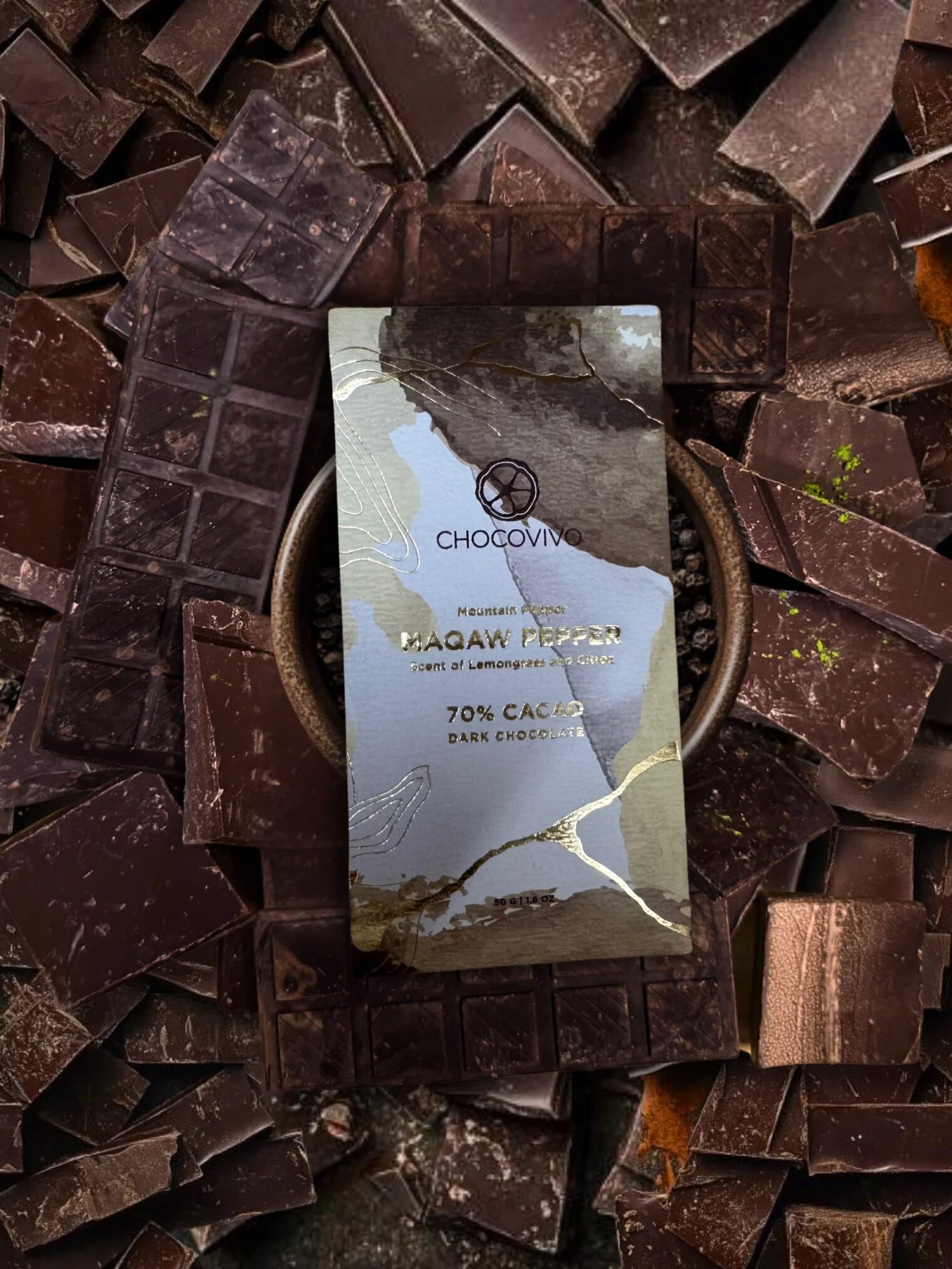 A ChocoVivo Lagav Pepper 70% cacao dark chocolate bar is placed on a bowl, surrounded by broken pieces of dark chocolate.