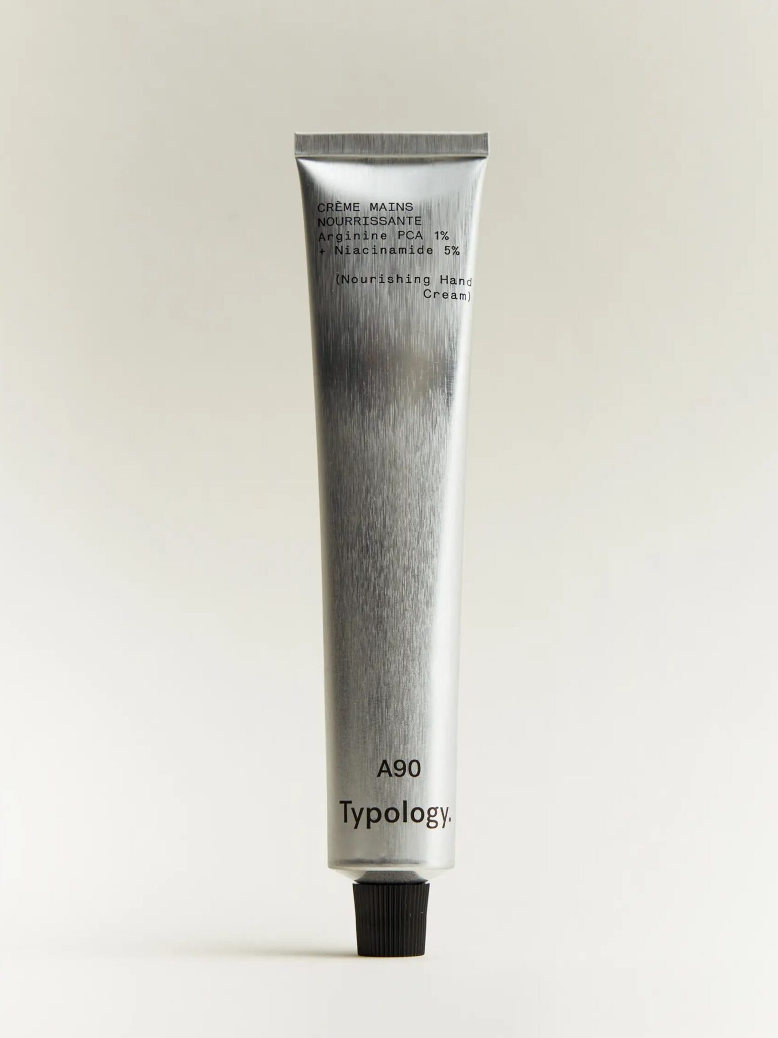 A metallic tube labeled "A90 Typology" contains nourishing hand cream, standing upright against a plain, light background.